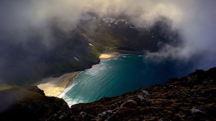 Aerial view of a secluded beach cove with turquoise water and mountains