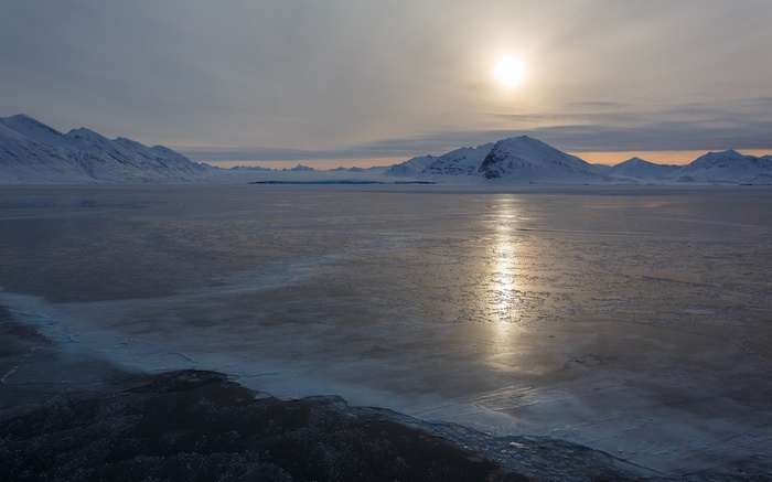 Frozen landscape with mountains and sun
