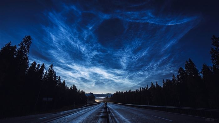 Noctilucent clouds over a road at night