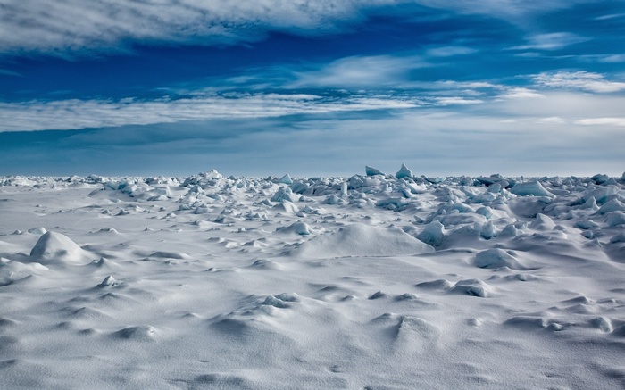 Arctic ice floes under a cloudy blue sky