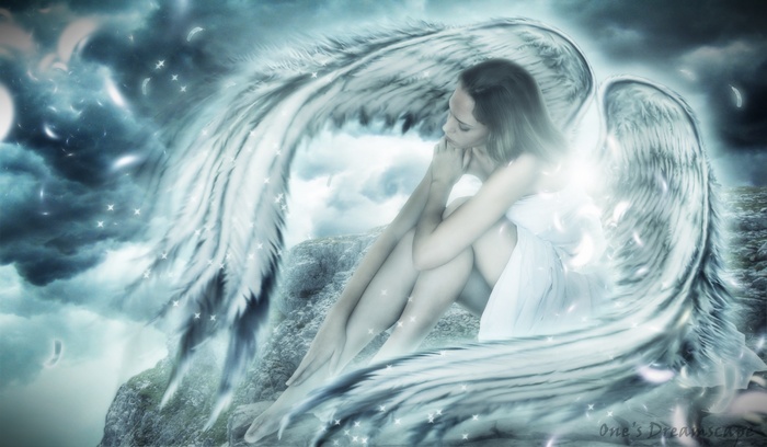 Angel girl with large wings sitting on rocks