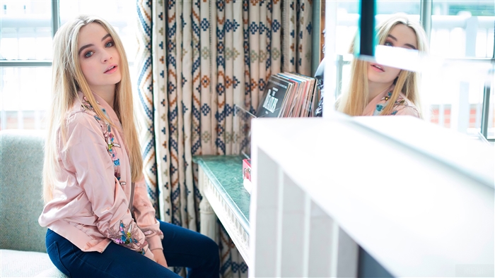 Sabrina Carpenter sitting by a window
