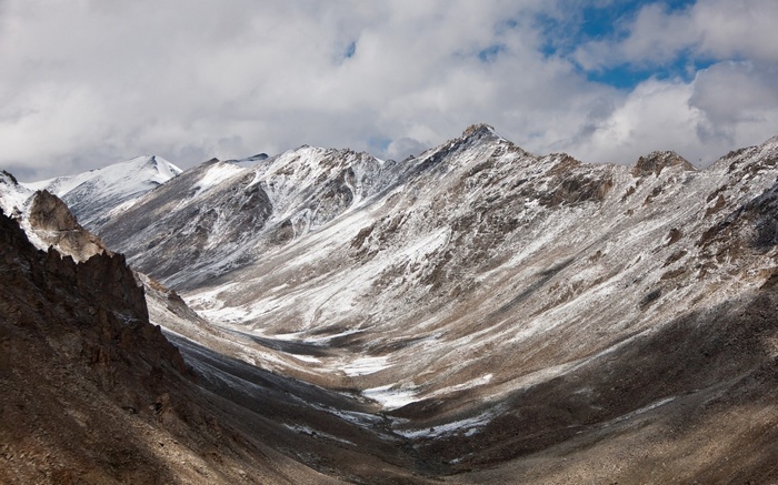 Snow-dusted mountains in a valley under a cloudy sky