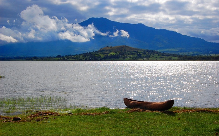 Canoe on the shore of a lake with mountains in the background