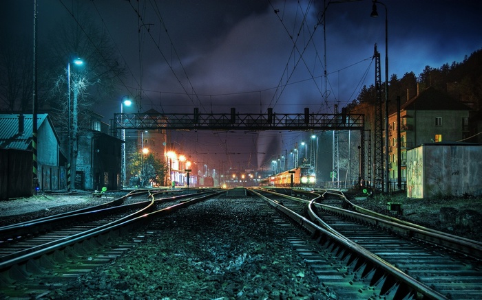 Train tracks at night with train and lights