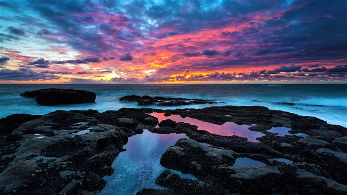 Vibrant Sunset Over Rocky Seashore with Waves