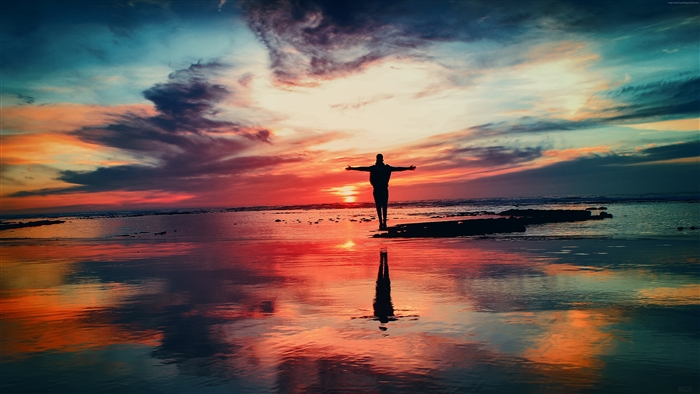 Man with arms outstretched at sunset over the sea