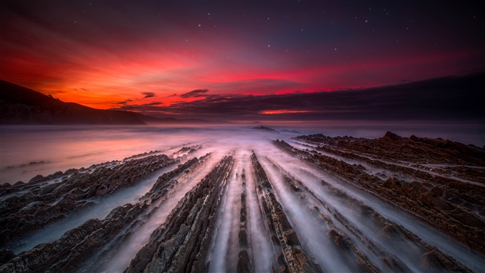 Sea sunset over rocky shore with mist