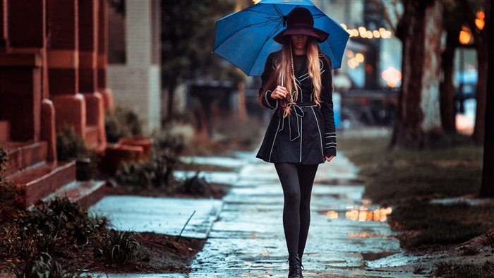 Woman with umbrella walking on wet sidewalk