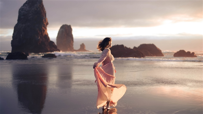 Woman in pink dress on beach with sea stacks