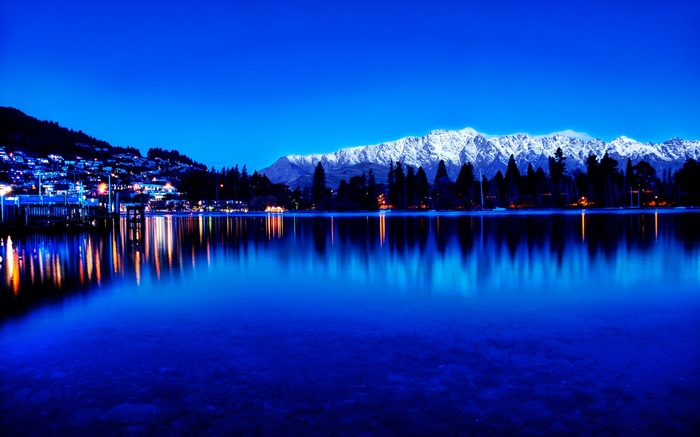 Snow-capped mountains reflected in a lake at dusk