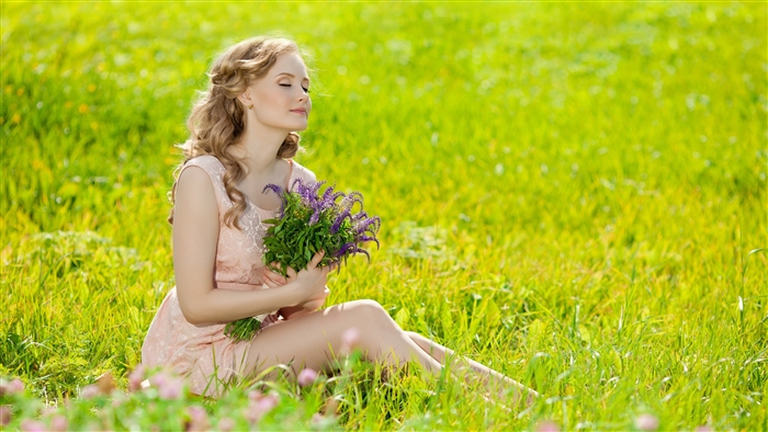 Woman in a pink dress holding flowers in a field