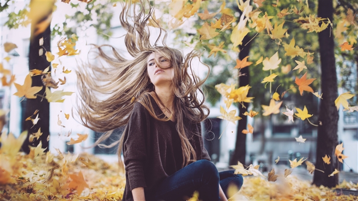 Woman with windblown hair in autumn leaves