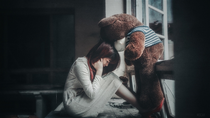 Girl and teddy bear by window