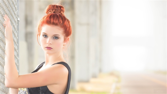 Young woman with red hair by fence