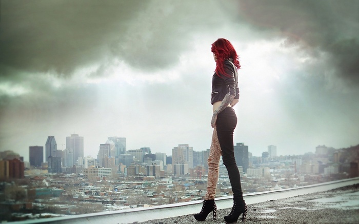 Woman with tattoos and red hair overlooking a city