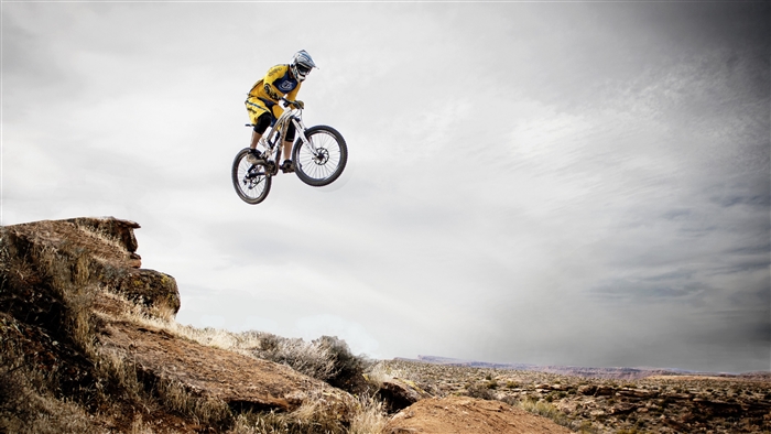 Mountain biker jumps over a rocky cliff