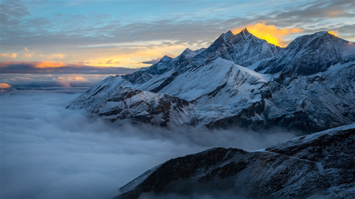 Snowy mountain peaks above clouds at sunrise 4K
