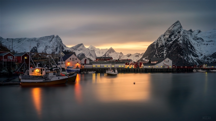 Fishing village with snow-capped mountains at dusk