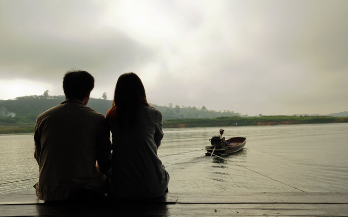 Couple watching a boat on a misty lake