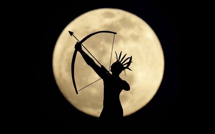 Silhouette of an archer with a bow and arrow against the moon