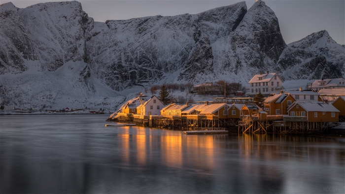 Snowy mountains and yellow houses by the water