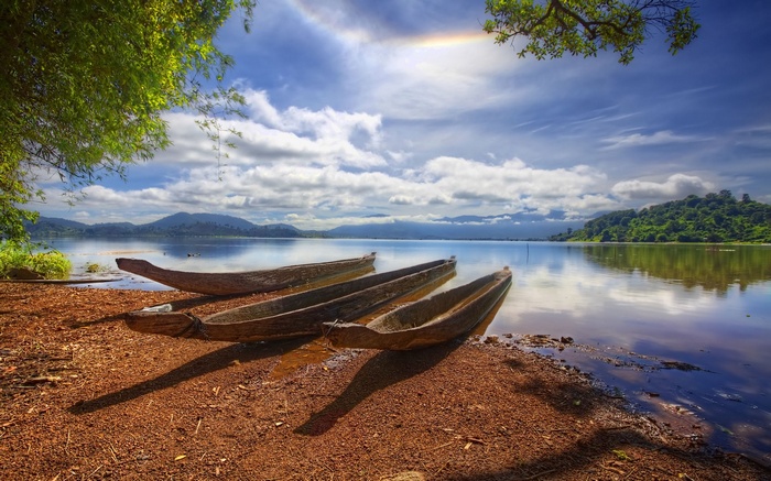 Wooden canoes on a lake shore with mountains in the background