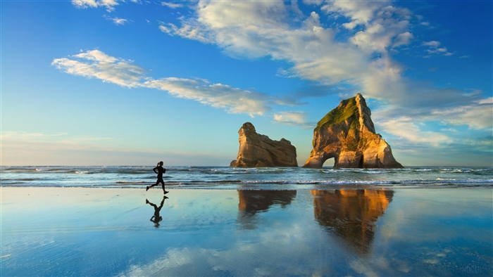 Woman running on a beach with rock formations