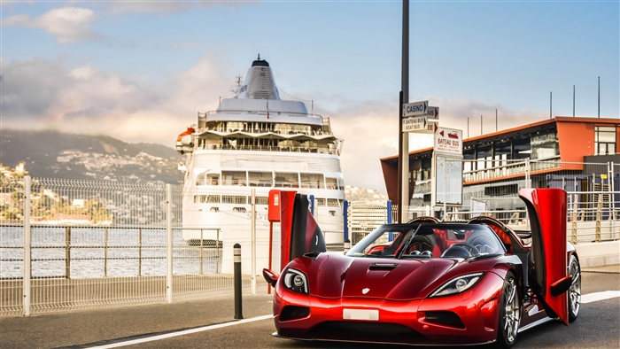 Red Koenigsegg Agera R parked by a cruise ship