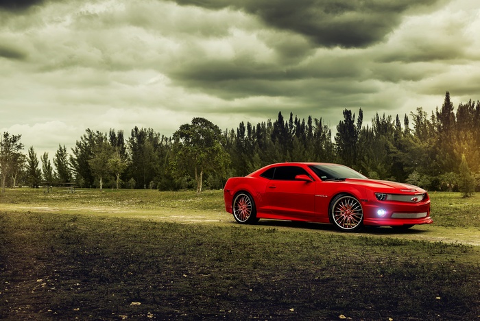 Red Chevrolet Camaro parked on a dirt road