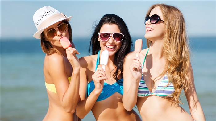 Three Women Enjoying Ice Cream on Sunny Beach