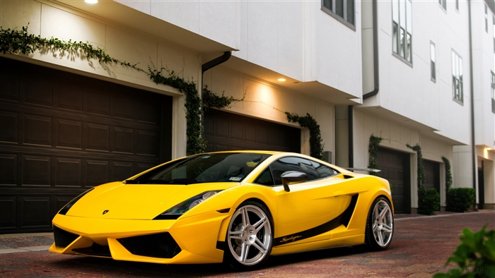 Yellow Lamborghini Gallardo parked in front of garages