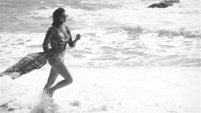 Woman in bikini and shirt running on beach