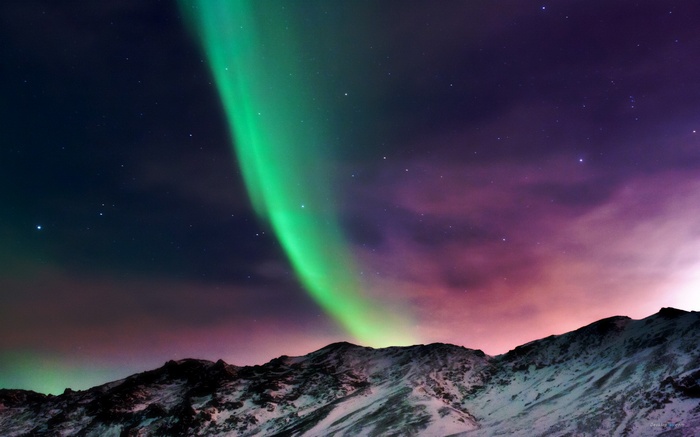 Aurora Borealis over snow-covered mountains at night