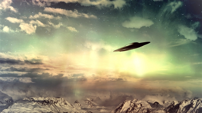 UFO flying in a cloudy sky over mountains
