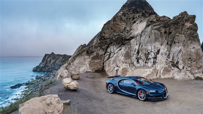 Blue Bugatti Chiron supercar on a rocky coast