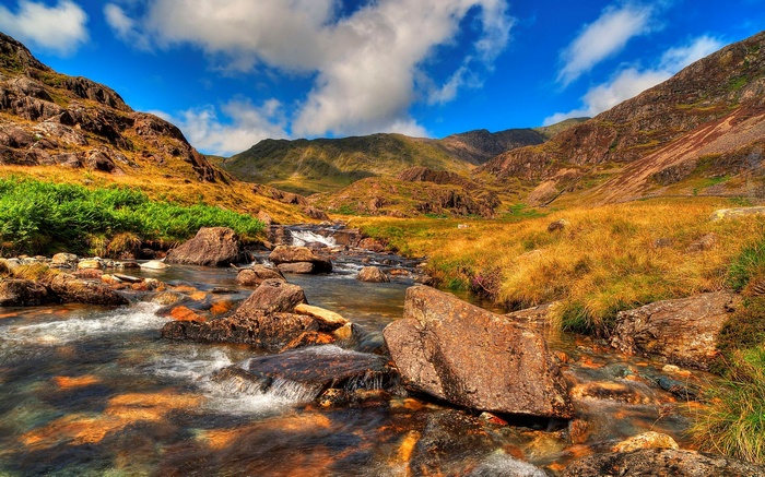 Mountain stream flowing through rocky terrain under a blue sky