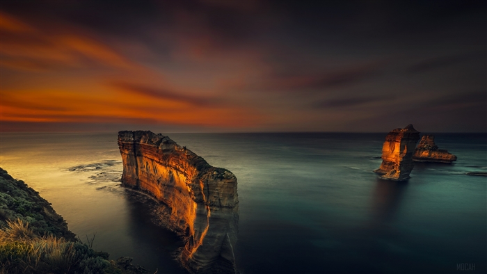 Rock formations in the ocean at sunset