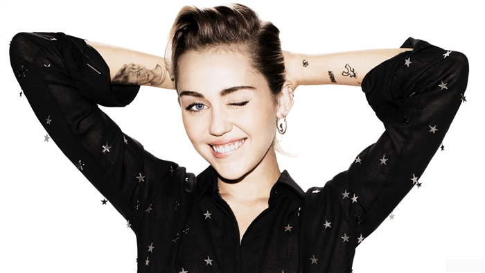 Miley Cyrus winks with hands behind head