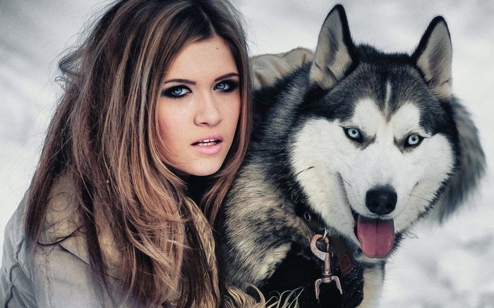 Girl with blue-eyed husky dog in snow