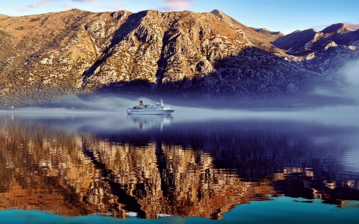 Cruise ship on a misty bay with mountains