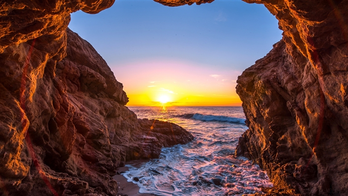 Sunset Over Ocean Viewed Through Cave Entrance