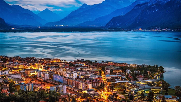 Evening view of a town by a lake and mountains in Switzerland 4K