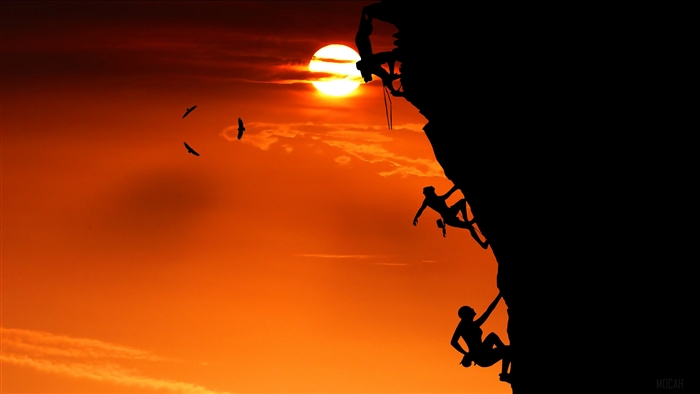 Rock climbers silhouetted against a sunset