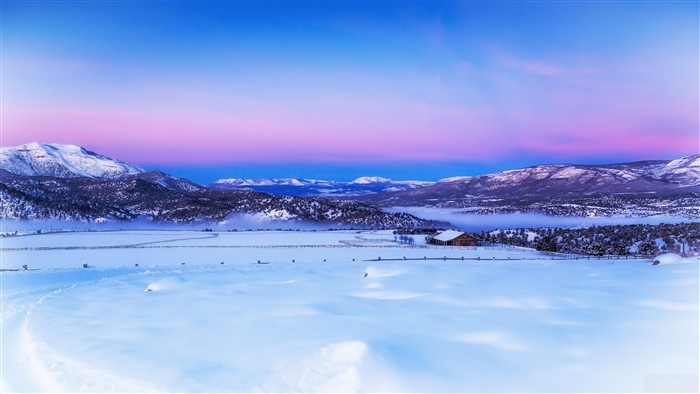 Winter landscape with snow-covered mountains and a cabin