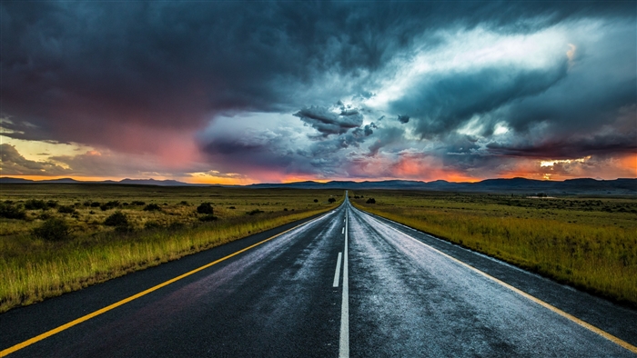 Road through a landscape under stormy clouds
