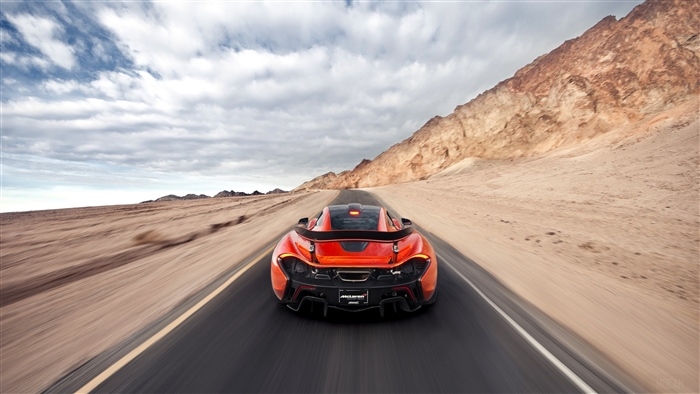 Orange McLaren P1 driving on a desert road