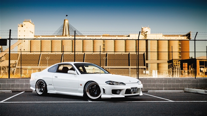 White Nissan Silvia S15 parked in front of industrial silos