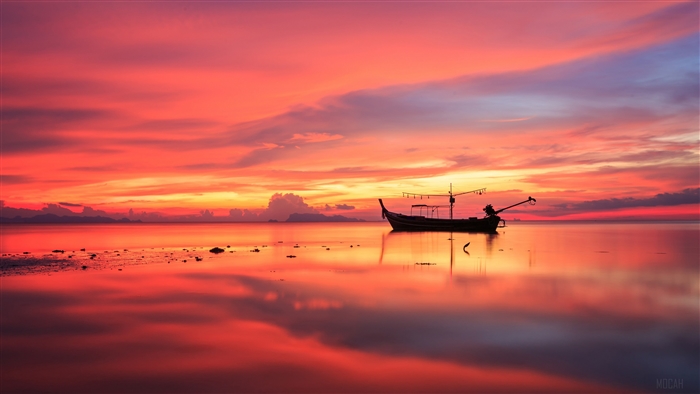 Fishing boat on the horizon during a colorful sunset with reflection