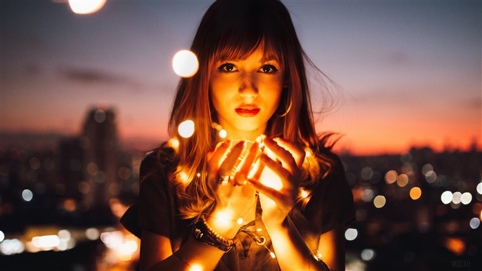 Woman holding fairy lights at dusk